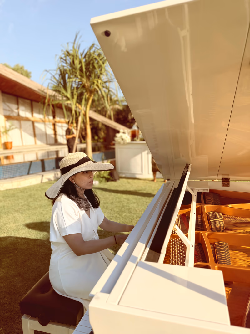 Wedding pianist performing on a white grand piano in a garden setting in Bali