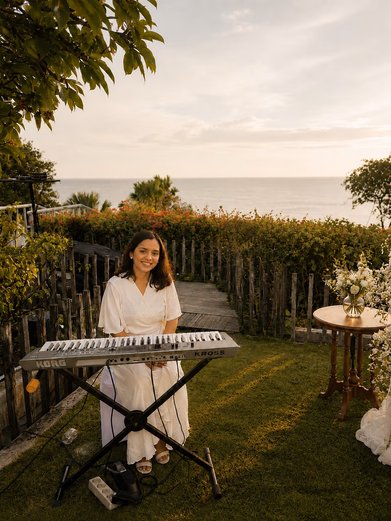 Wedding pianist performing in a garden pathway at sunset in Bali